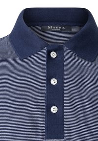 Námořnické pruhované polo tričko s límečkem a třemi bílými knoflíky. Tkanina má texturovanou strukturu s kontrastními pruhy.