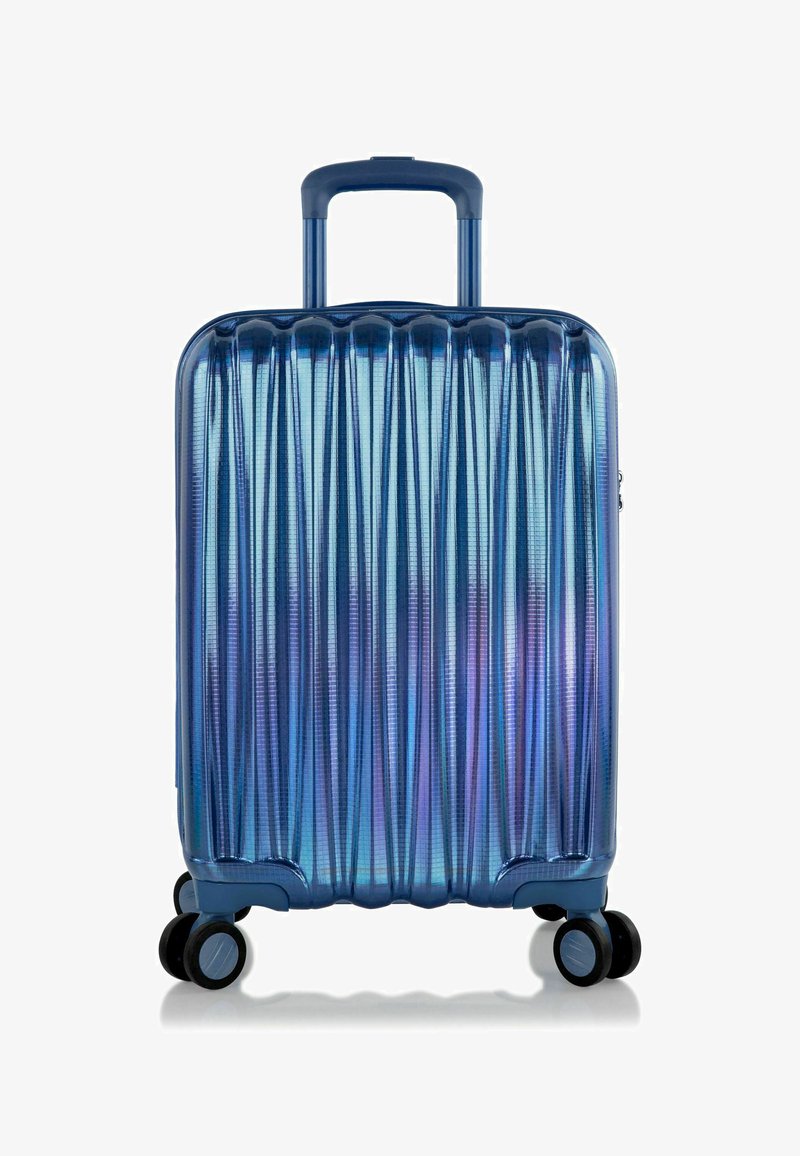 Valigia rigida in tonalità blu sfumate, con texture a righe, maniglia retrattile e quattro ruote nere per la mobilità.