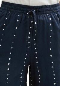 Navy blue drawstring pants with a relaxed fit, featuring irregular white polka dots and an elastic waistband for comfort.