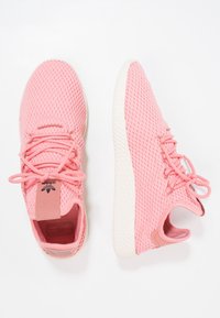Rosa sportskor med meshinstrument, snörning, vadderad krage och vit texturerad sula. Har en logotagg på tungan.