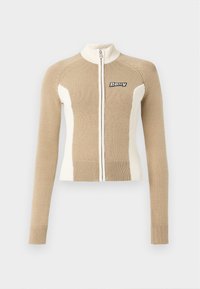 Strikket zip-up genser i beige og krem med lange ermer, ribbede mansjetter og kontrastpaneler. Har en logo på venstre bryst.