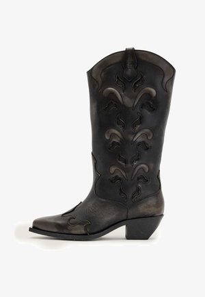Schwarzer Leder-Cowboystiefel mit dekorativer Stickerei und Cutout-Mustern, schrägem Absatz und spitzer Zehe, seitlich betrachtet.