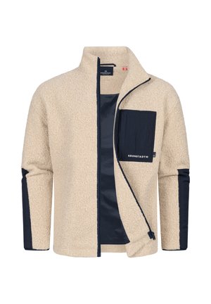 Beige fleece takki, jossa on laivastonsiniset yksityiskohdat, vetoketjullinen etuosa, korkea kaulus ja rintatasku. Pehmeä textura ja kontrastiväriset paneelit hihoissa.