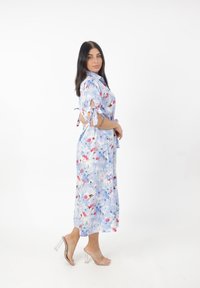 Bloemenjurk gemaakt van lichtgewicht stof, met een zachte blauwe basis en rode en roze accenten, korte mouwen met strikdetails en een ontspannen pasvorm.