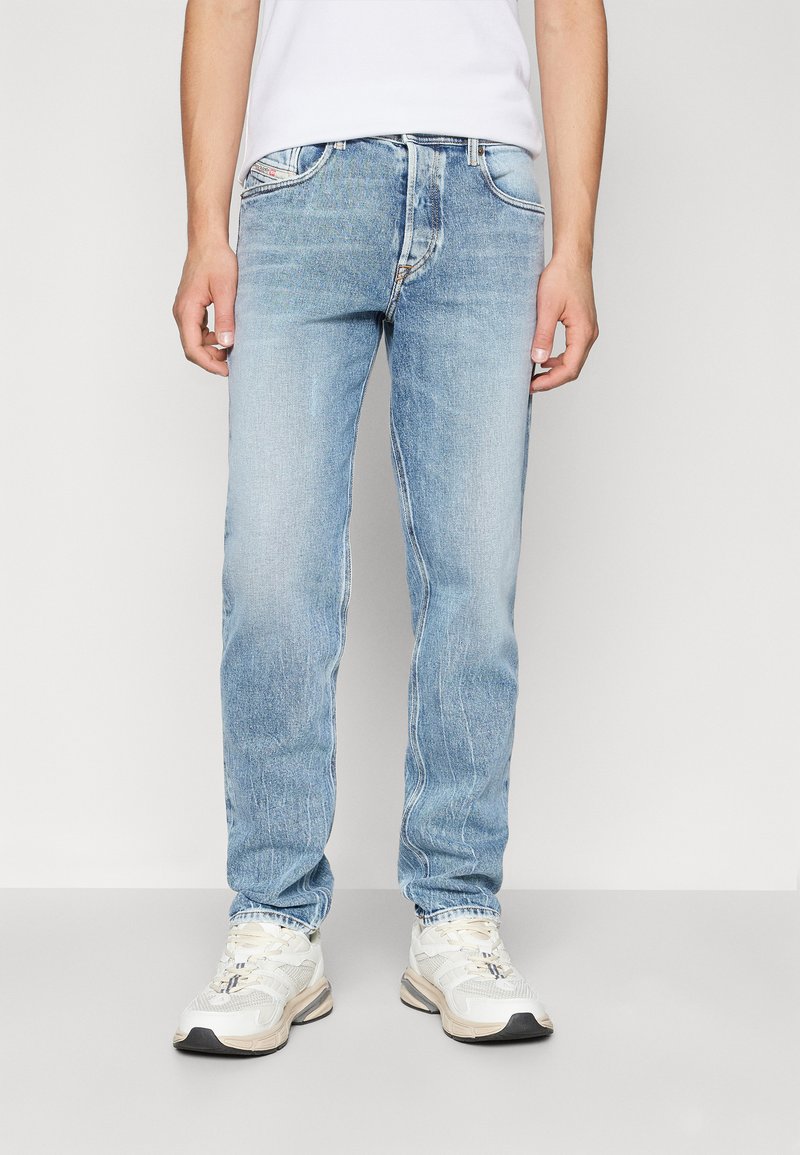 Jeans de mezclilla azul claro con un diseño de pierna recta, textura deslavada y detalles sutiles en la costura. Combinados con zapatillas blancas.