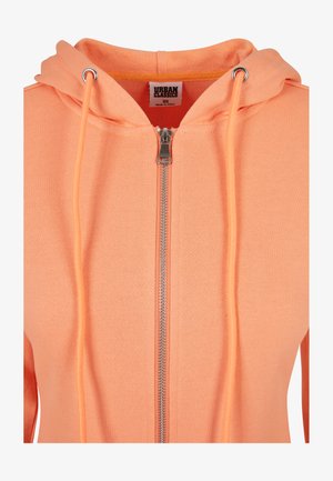 Haut à zip orange fabriqué en tissu doux avec une finition texturée, comprenant une fermeture éclair en métal et des cordons de serrage, ainsi qu'une capuche pour une protection supplémentaire.
