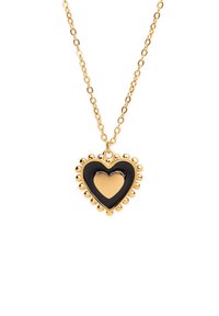 Collar con colgante de corazón en tono dorado que presenta un corazón interior de esmalte negro y un borde de cuentas. La cadena es de estilo clásico de eslabones.