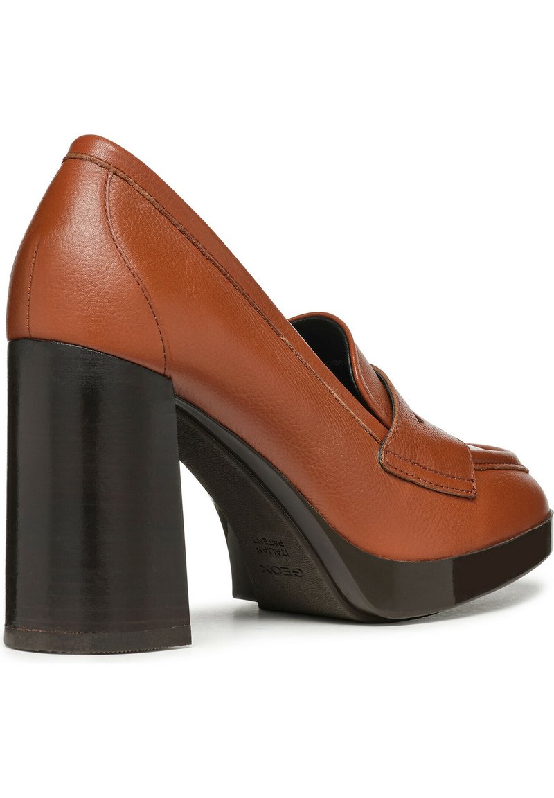 Mocassino alto in pelle marrone con tacco a blocco nero spesso e suola con piattaforma su sfondo bianco.