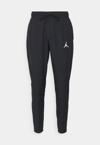 Černé sportovní kalhoty s tapered střihem, elastickým pasem a šňůrkou na stažení. Na levém stehně se nachází bílé logo Jordan.