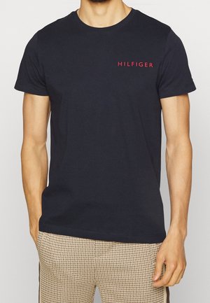 Navy blue cotton t-shirt featuring short sleeves and a small red "HILFIGER" logo on the left chest. Simple, classic design.