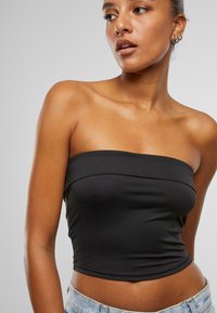 Top negru fără bretele, cu un design ajustat, fabricat din material ribbat, având un decolteu drept și fără închideri vizibile.