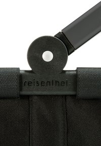 Zwarte stoffen vouwstoel met ronde zwarte bevestigingen, voorzien van versterkte stiksels en het logo "reisenthel" geembossed op de rand.
