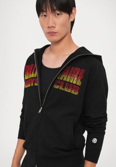 Crna zip-hoodie sa šarenim gradijentnim tekstom "Billionaire Boys Club" na prsima i logom na rukavu. Glatka tkanina, ležeran kroj.