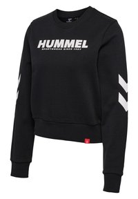 Czarna bluza z długim rękawem i okrągłym dekoltem, z białym napisem „HUMMEL” i logo w kształcie jodełki na rękawach, ściągaczami na mankietach i dole oraz małą czerwoną metką blisko dołu.