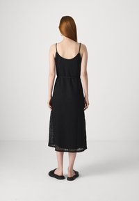 Černé krajkové midi šaty s výstřihem na zádech, tenkými nastavovacími ramínky a detailem v pase, se skládající z vrstveného designu s poloprůhledným zakrytím.