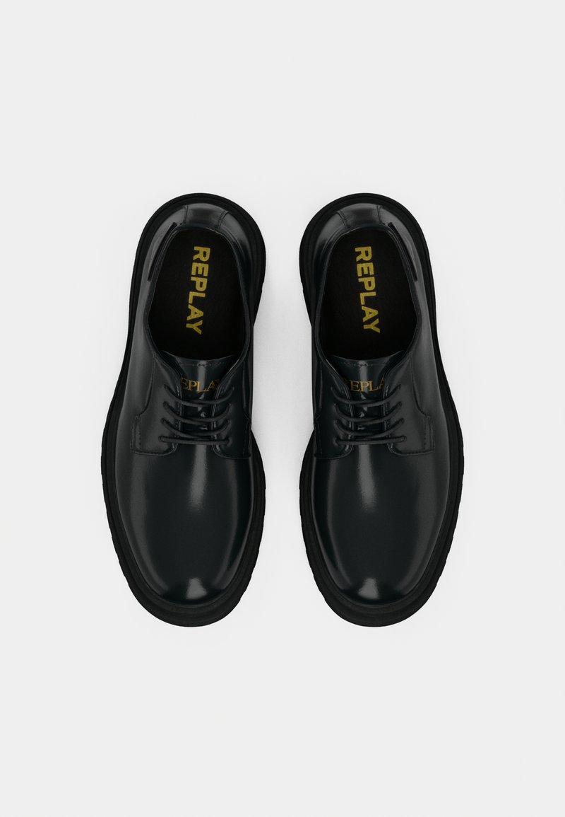 Zapatos de cuero negro con acabado brillante, diseño de cordones, punta redonda y suela de goma negra contrastante. Logo dorado "REPLAY" en las plantillas.