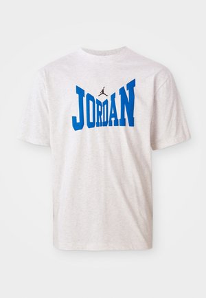 T-shirt gris à manches courtes avec le texte "JORDAN" en bleu vif et un logo Jumpman noir, fabriqué en coton doux.