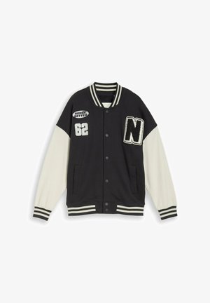 Veste universitaire noire et blanche avec col et poignets rayés, écusson "N", numéro "62" et texte "Never Better" sur le devant.