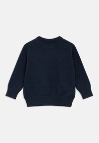 Πλεκτό πουλόβερ σε ναυτικό μπλε χρώμα με στρογγυλή λαιμόκοψη, μακριά μανίκια και ριμπ μανσέτες και τελείωμα. Απαλή υφή με κλασική γραμμή, χωρίς εμφανή λογότυπα.