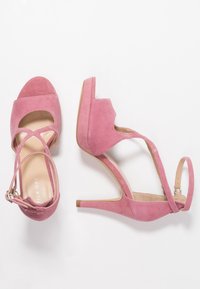 Sandalias de tacón alto de ante rosa con tira en el tobillo, punta abierta, diseño recortado y un resistente tacón de aguja. Forro interno suave.