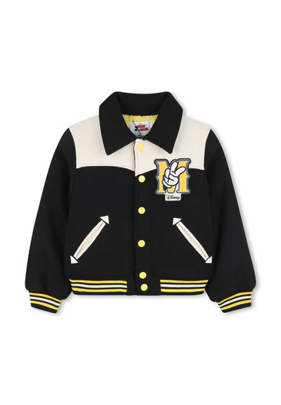 Giacca in stile varsity nera e crema con bottoni gialli, polsini a righe e un logo 'M' con un design di segno di pace sul petto.