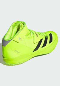 Chaussure de sport jaune néon avec des rayures noires, bout arrondi, col rembourré et panneaux texturés. Fabriquée en matériau léger et dotée d'une semelle en caoutchouc.