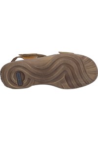 Brown rubber sandal sole with textured pattern, grooves, and a logo detail. Features multiple straps with a soft finish.