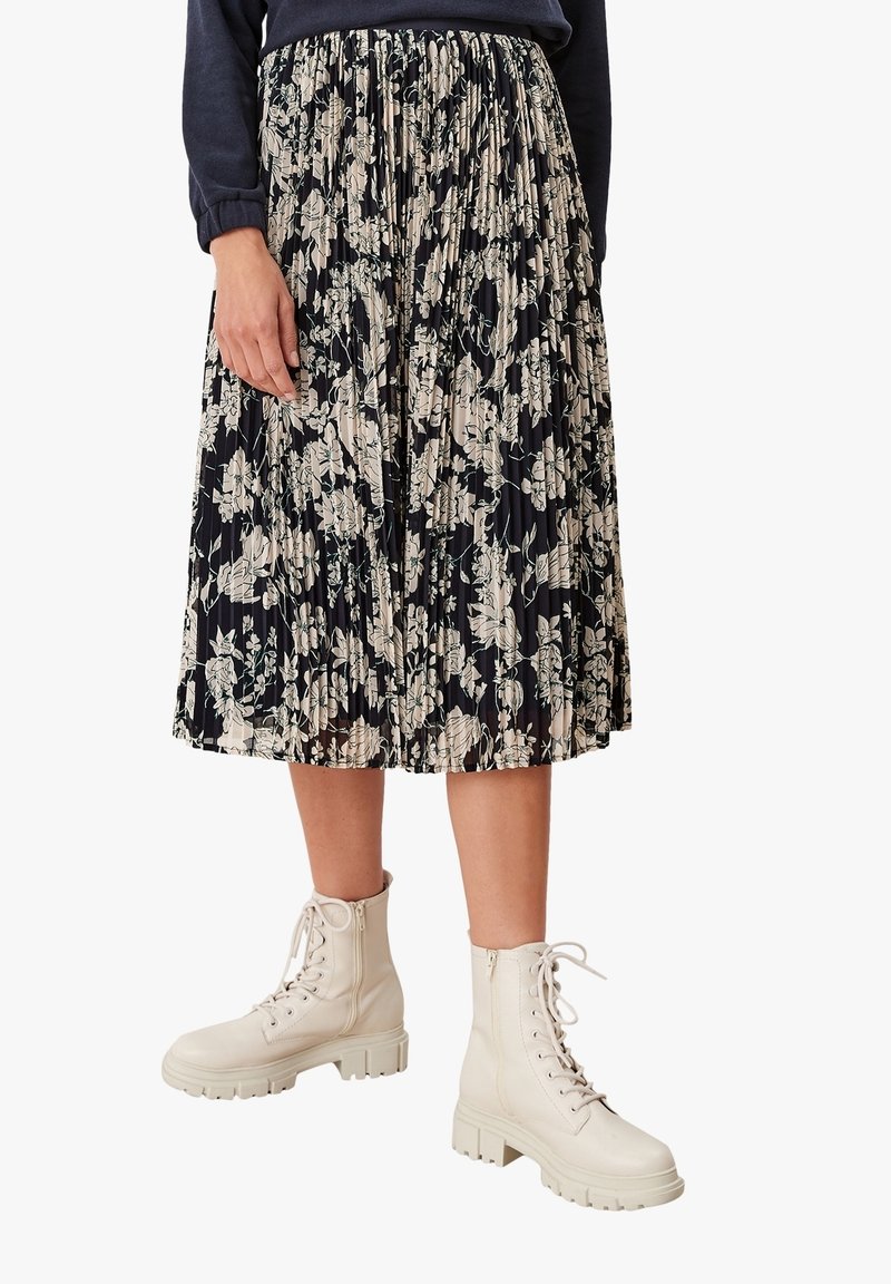 Plisserad midikjol i mörkblått med vitt blommönster. Kombinerad med vita snörkängor. Kjolen har ett elastiskt midjeband.