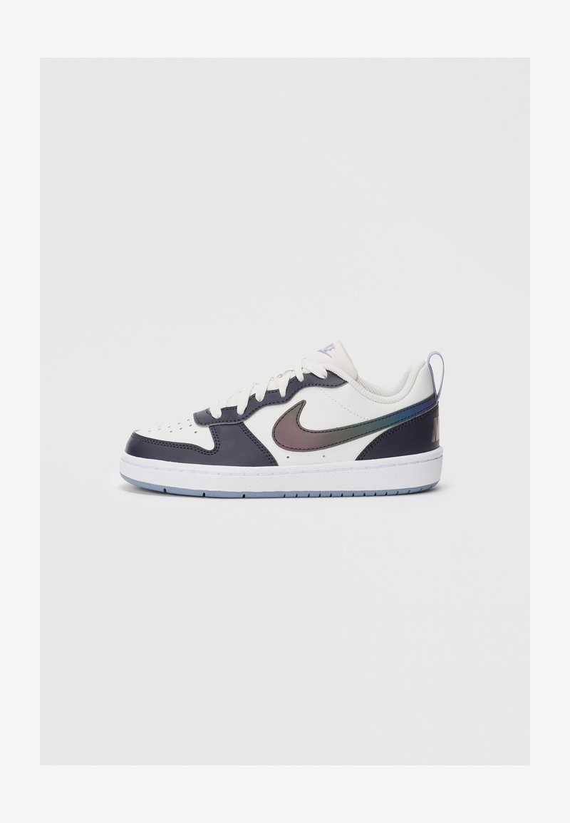 Tenis Nike cu aspect alb și negru, de tip low-top, cu swoosh iridescent, șireturi albe și talpă de un albastru deschis, prezentat din profil lateral pe un fundal alb.