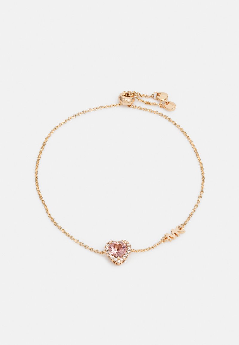 Pulsera en tono dorado con una delicada cadena, que presenta una gema rosa en forma de corazón rodeada de piedras claras y un pequeño acento de logo.