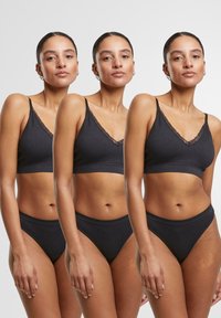 Black ribbed bralette with lace trim and adjustable straps, paired with matching high-waisted black briefs. Smooth texture, minimalist design.