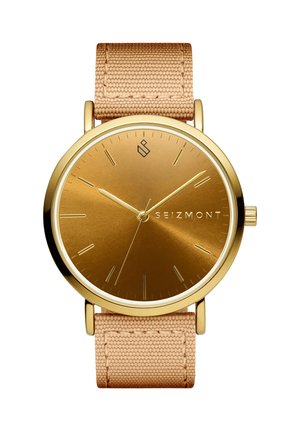 Armstikk i gulltoner med minimalistisk urskive, gullmarkører, beige vevd stropp og merkenavnet "Seizmont" på høyre side av urskiven.