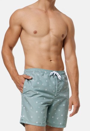 Shorts de bain verts avec des motifs nautiques blancs. Comprend une taille élastique avec cordon, des poches latérales et une texture lisse.