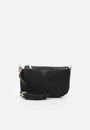 Sac bandoulière noir Guess avec sangle ajustable, ferrures dorées et plaque triangulaire du logo à l'avant sur fond clair uni.