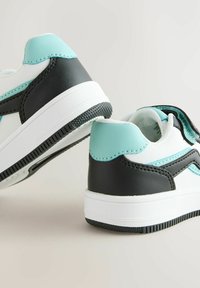 Witte en zwarte sneakers met turquoise accenten. Heeft een bovenwerk van glad leer, een ronde hak, een gestructureerde zool en stikseldetails.