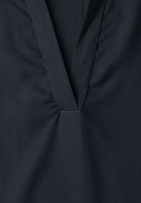 Tissu bleu marine foncé avec un profond décolleté en V présentant un détail de couture froncée au centre devant.