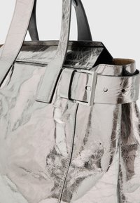 Metallic sølv tote taske med en tekstureret overflade, der har en rektangulær form, dobbelte håndtag og en spænde detalje på remmen.