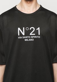 Černé síťované tričko s bílým textem "N°21 VIA SANTO SPIRITO MILANO", kulatý výstřih, krátké rukávy a prodyšná textura.