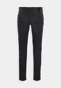 Jeans ajustados de mezclilla negra con una textura suave, que cuentan con dos bolsillos traseros y una cinturilla con marca. Diseño minimalista sin adornos visibles.