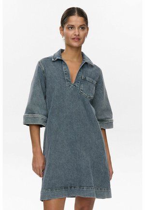 Jeanskleid in verblasstem Blau, mit V-Ausschnitt, übergroßem Kragen, 3/4-Ärmeln und einer Brusttasche. Weiche Textur und lässige Silhouette.