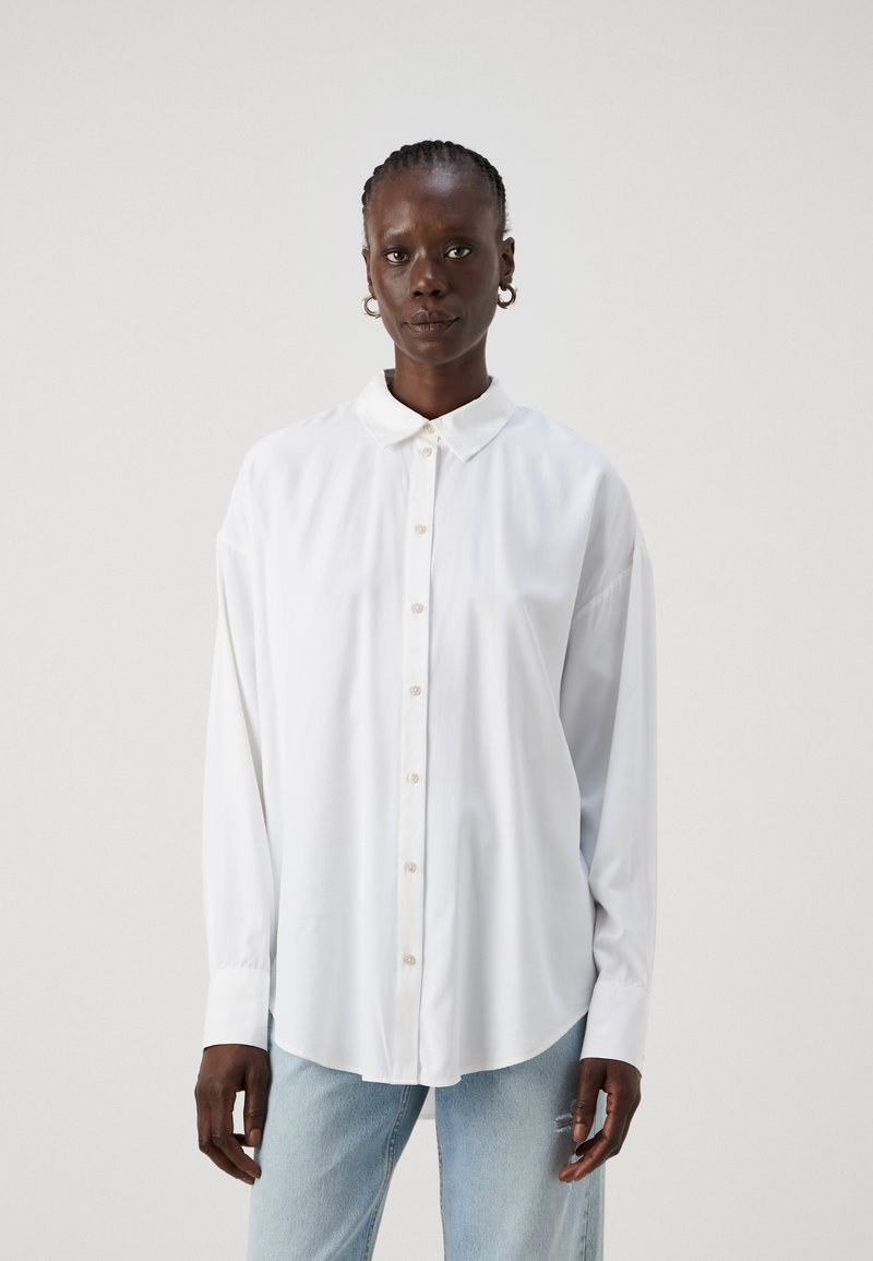 White long-sleeve shirt with a button-down collar, front buttons, and a relaxed fit. The fabric appears smooth and lightweight.