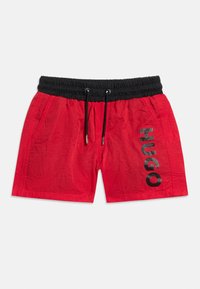 Κόκκινα σορτς κολύμβησης με μαύρη ελαστική μέση και κορδόνι, πλαϊνές τσέπες και το λογότυπο "HUGO" τυπωμένο κάθετα στο δεξί πόδι.