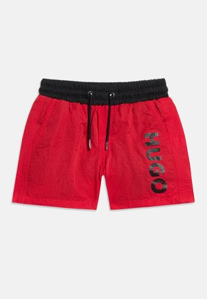 Κόκκινα σορτς κολύμβησης με μαύρη ελαστική μέση και κορδόνι, πλαϊνές τσέπες και το λογότυπο "HUGO" τυπωμένο κάθετα στο δεξί πόδι.