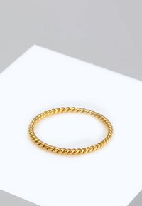 Goldener, gedrehter Ring mit einer glatten, abgerundeten Oberfläche. Das Design zeichnet sich durch abwechselnde Drehungen aus, die eine strukturierte und reflektierende Erscheinung erzeugen.