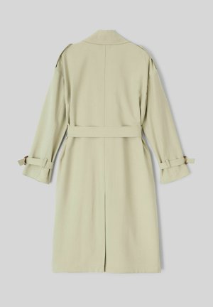 Trench-coat vert clair en tissu lisse, avec une taille ceinturée, des manches longues et des poignets retroussés. La vue de dos montre un design à coupe droite.