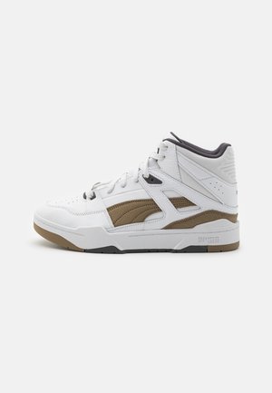 Hvid højtop Puma sneaker med brun ruskindsside og en tyk hvid sål på en ensfarvet baggrund.