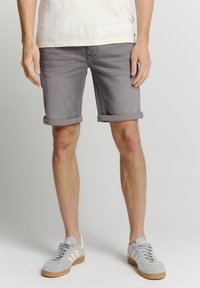Grijze denim shorts met opgerolde zomen, een platte voorkant en zijzakken; gecombineerd met lichtgrijze sneakers met witte strepen.