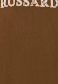 T-shirt marrone con tessuto testurizzato. Grande lettering bianco ricamato al centro, che recita "RUSSARD" nella zona del petto.