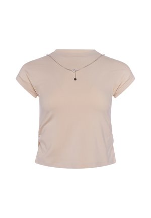 Top corto beige a maniche corte con scollatura rotonda e una sottile collana d'argento con una piccola perla e ciondolo su sfondo bianco.