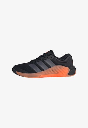 Chaussure de sport noire avec des rayures grises et une semelle orange épaisse, vue de côté sur fond blanc.